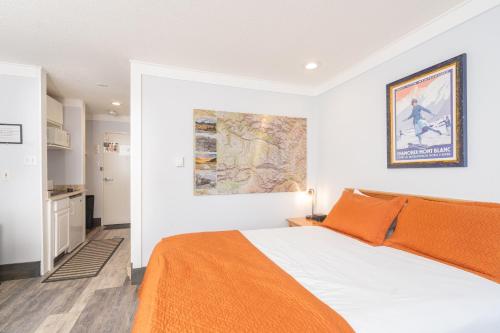 a bedroom with a bed with an orange blanket at Mountainside Inn 103 by Alpine Lodging Telluride in Telluride