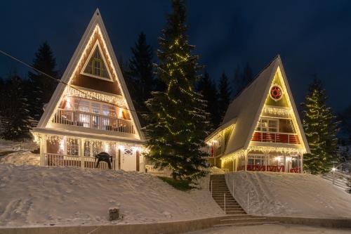 Una casa con luces de Navidad en la nieve en Двоповерховий апартамент у котеджі Freeman-3b з грилем та альтанкою - СВІТЛО Є ЗАВЖДИ, en Bukovel