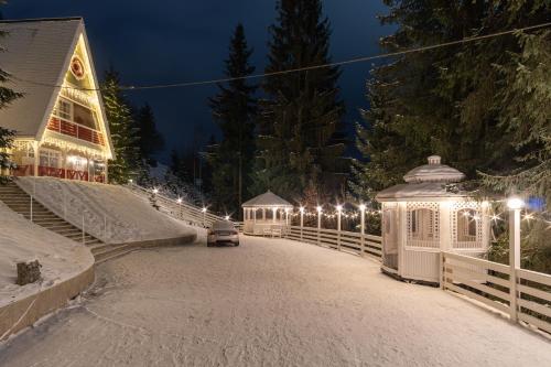 Una calle nevada con un edificio con luces por la noche. en Двоповерховий апартамент у котеджі Freeman-3b з грилем та альтанкою - СВІТЛО Є ЗАВЖДИ, en Bukovel