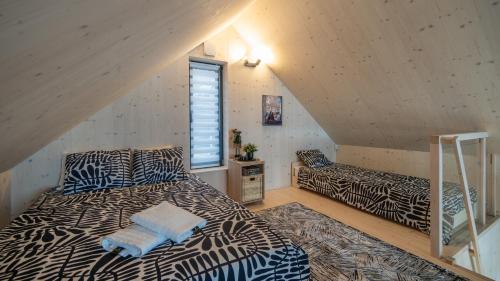 a attic bedroom with two beds and a window at Muchatki domki z sauną in Zagórze