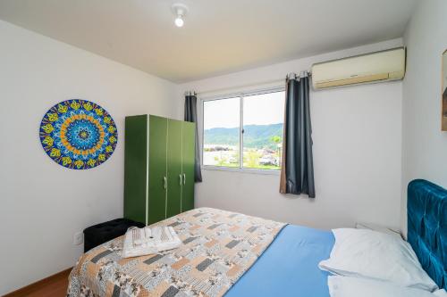 a bedroom with a bed with a green cabinet and a window at Acomodações Azaleias by Rental in Palhoça