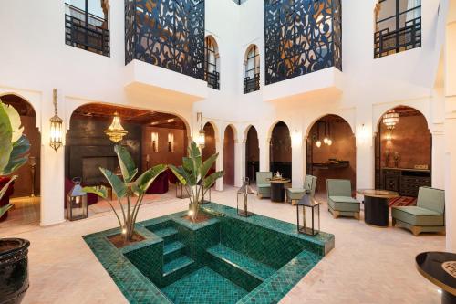 a pool in the middle of a lobby with chairs and tables at Riad Dar Acsameda & Spa in Marrakech