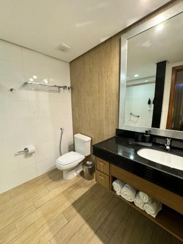 a bathroom with a toilet and a sink and a mirror at Radisson Belém - Flat in Belém
