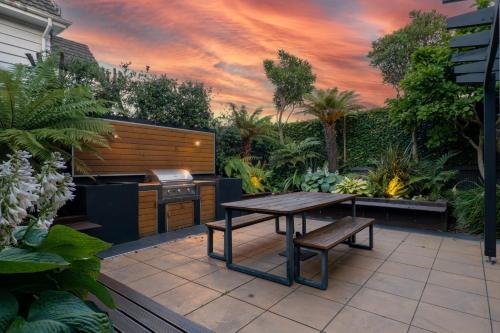 a patio with a table and bench and a grill at Luxurious Central City Living in Christchurch
