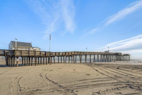a wooden pier on the beach with a house at Renovated Ocean City Retreat - Walk to Beach! in Ocean City