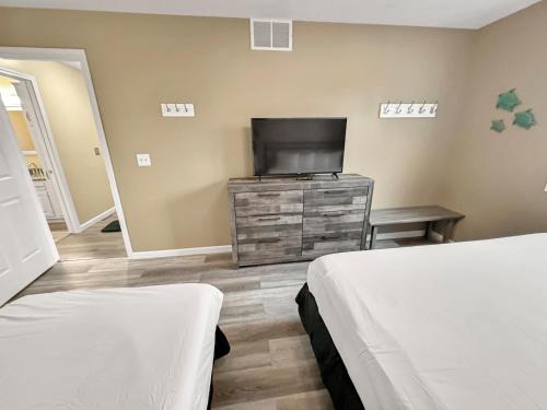 a bedroom with two beds and a flat screen tv at On Island Time at Kelleys Island Condo! in Kelleys Island