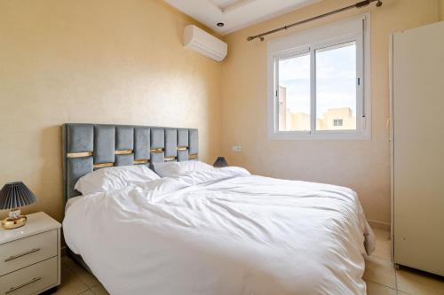 a bedroom with a large white bed with a window at luxury appartement near gueliz voyageurs in Marrakech