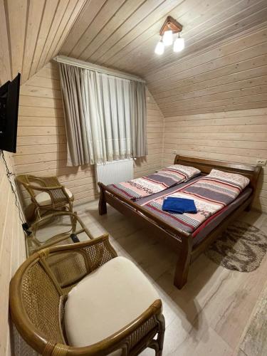 a bedroom with a bed and two chairs in a room at Котедж Зґарда in Yaremche