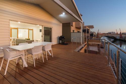 a wooden deck with a table and chairs on a balcony at Exmouth Retreat - 3x3 on the canals in Exmouth