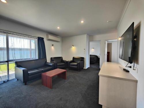 a living room with a couch and chairs and a flat screen tv at Camden Court Apartment in Invercargill