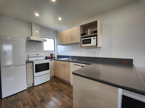 a kitchen with white appliances and a black counter top at Camden Court Apartment in Invercargill