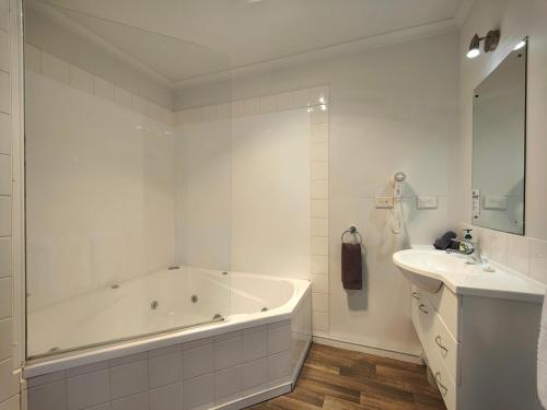a white bathroom with a tub and a sink at Camden Court Apartment in Invercargill