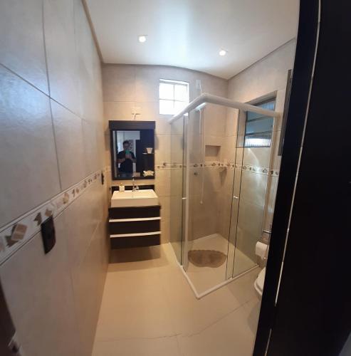 a bathroom with a shower and a sink and a mirror at Sobrado pertinho da praia in Capão da Canoa