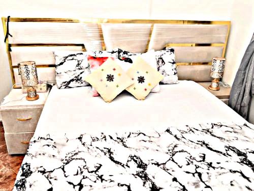 a bed with black and white sheets and pillows at Luxury 3-bedroom apartments 5-min to the Airport in Fès