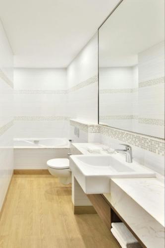 a white bathroom with two sinks and a toilet at Fairfield by Marriott Kolkata in Kolkata