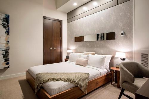 a bedroom with a large bed and a chair at Courtyard by Marriott Calgary South in Calgary