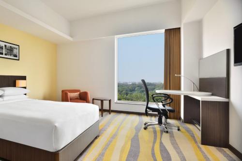 a hotel room with a bed and a desk and a window at Fairfield by Marriott Ahmedabad in Ahmedabad