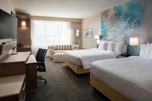 a hotel room with two beds and a couch at Courtyard by Marriott Irvine Spectrum in Irvine