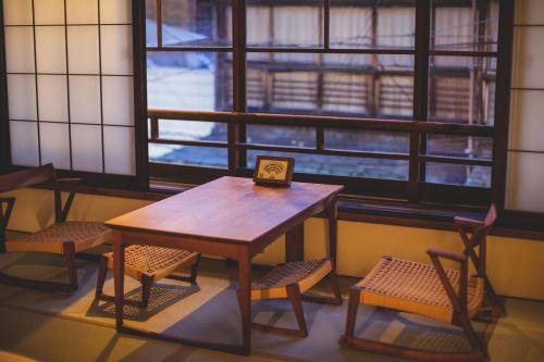 a table and chairs in a room with windows at Koyado Surugatei in Kobe