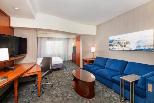 a hotel room with a blue couch and a bed at Courtyard by Marriott Santa Ana Orange County in Santa Ana