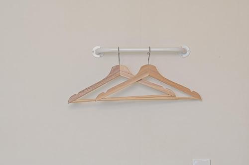 a rack with four wooden hangers on a white wall at In Stay Guesthouse in Seogwipo