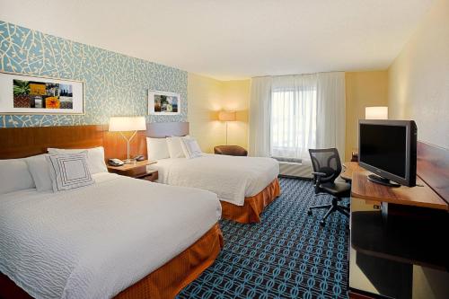 a hotel room with two beds and a flat screen tv at Fairfield by Marriott Southeast Hammond, IN in Hammond