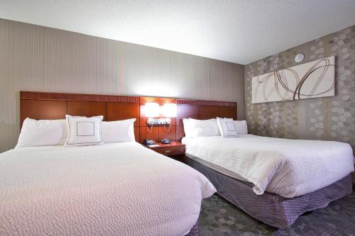 a hotel room with two beds with white sheets at Courtyard Blacksburg in Blacksburg
