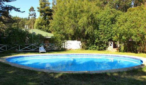 a small blue pool in a yard with a tree at Alta Vista de Cahuil in Pichilemu