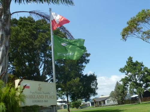 a flag and a sign in front of a park at At Parkland Place B&B in Whitianga