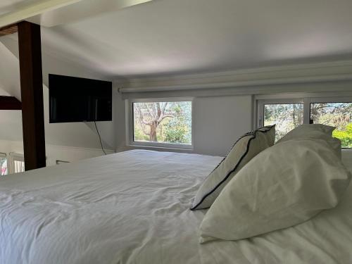 a bedroom with a white bed with pillows and a television at Tiny House Mercedes in Mercedes