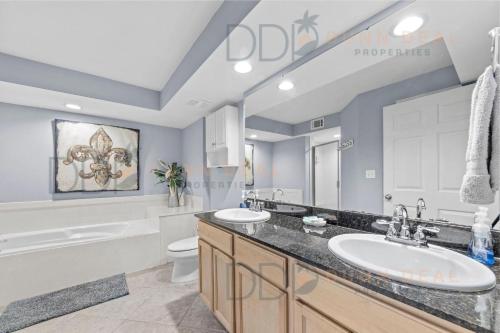 Un baño con dos lavabos, una bañera y un inodoro. en Ocean Club Villa B-220, en Biloxi
