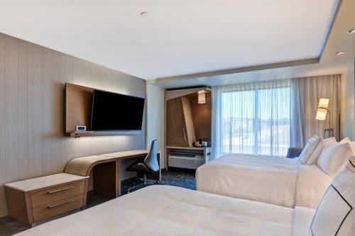 a hotel room with two beds and a desk and a television at Courtyard by Marriott Bentonville Rogers Promenade in Rogers