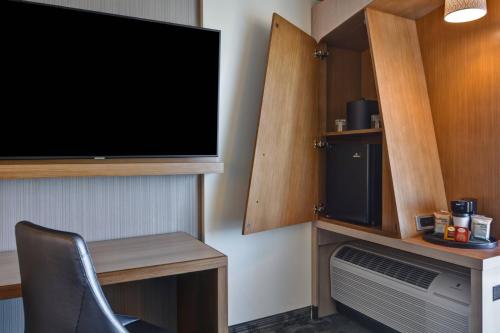 a tv on a wall with a desk and a chair at Courtyard by Marriott Bentonville Rogers Promenade in Rogers