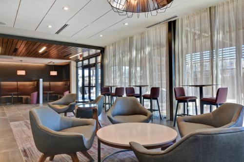 a waiting room with chairs and tables and windows at Courtyard by Marriott Bentonville Rogers Promenade in Rogers