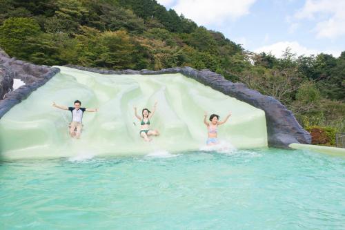 three people jumping off a water slide at a water park at Hakone Kowakien Miyamafurin in Hakone