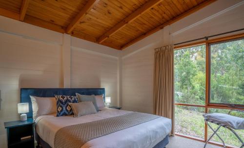 a bedroom with a bed and a large window at Stewarts Bay Lodge in Port Arthur