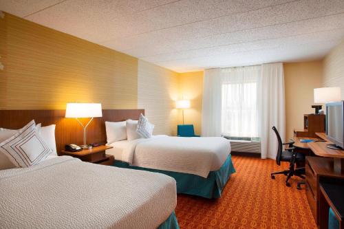 a hotel room with two beds and a desk at Fairfield Inn & Suites Chicago Midway Airport in Bedford Park