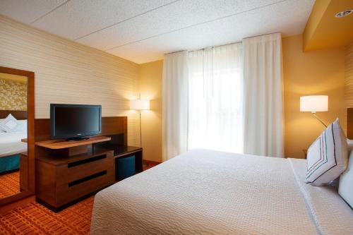a hotel room with a bed and a flat screen tv at Fairfield Inn & Suites Chicago Midway Airport in Bedford Park