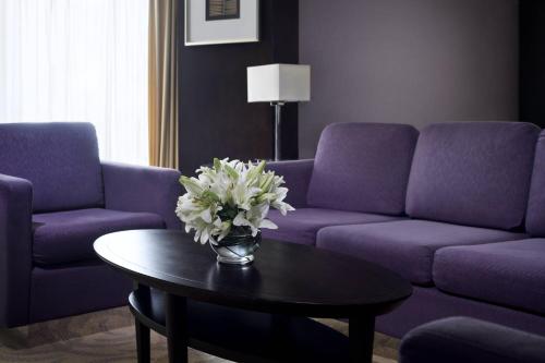 a living room with purple couches and a table with flowers at Courtyard by Marriott Riyadh Diplomatic Quarter in Riyadh