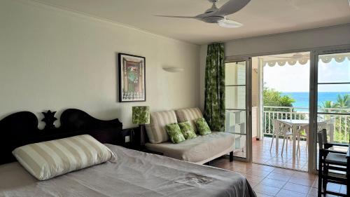 Un dormitorio con una cama y un balcón con vista al mar. en Studio vue mer, en Sainte-Anne