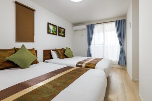 a hotel room with two beds and a window at New Villa! 15min drive to Naha airport# 2bathrooms in Itoman