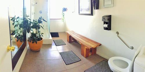 a bathroom with a toilet and a wooden bench at Hotel Royal in Long Beach