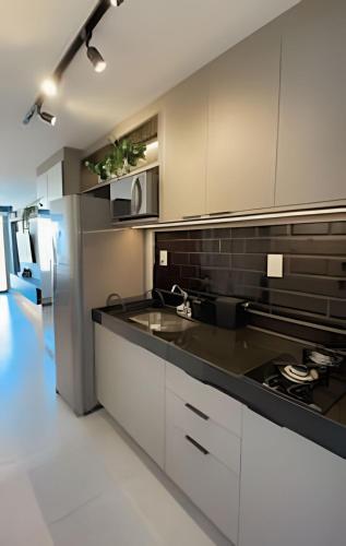 a kitchen with a sink and a refrigerator at Studio Luxo p/4 pessoas, a 50m do mar in Cabedelo