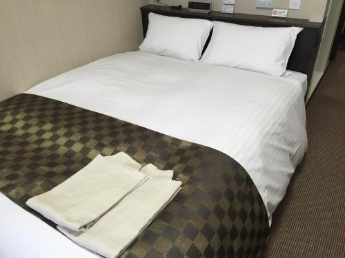 a bed with a pile of white sheets and pillows at Okawa Riverside Hotel in Ōkawa