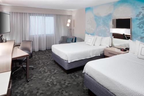 a hotel room with two beds and a desk at Courtyard Tuscaloosa in Tuscaloosa
