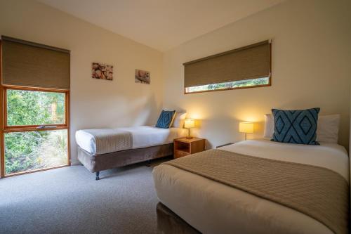 a bedroom with two beds and two windows at Stewarts Bay Lodge in Port Arthur