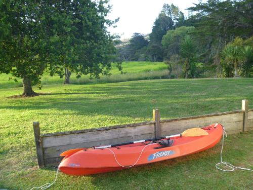 a red kayak is tied to a wooden fence at At Parkland Place B&B in Whitianga
