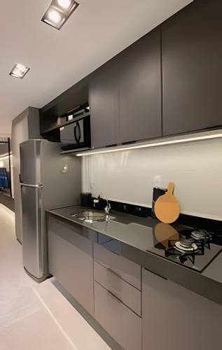 a kitchen with black cabinets and a stainless steel refrigerator at Loft luxo p/ 4 pessoas, a 50m do mar in Ilha da Restinga