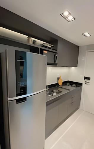 a kitchen with gray cabinets and a refrigerator at Loft luxo p/ 4 pessoas, a 50m do mar in Ilha da Restinga
