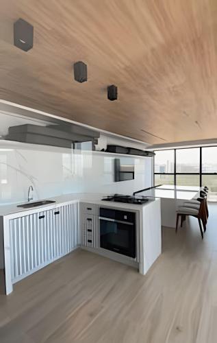 a kitchen with white cabinets and a large window at Loft luxo p/ 4 pessoas, a 50m do mar in Ilha da Restinga
